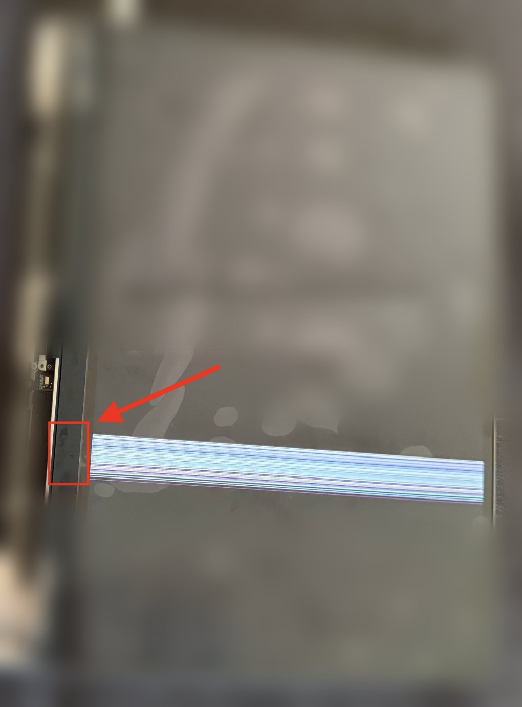 Banda horizontal de líneas de colores y manchas claras en una pantalla de MacBook desmontada: panel roto durante el montaje